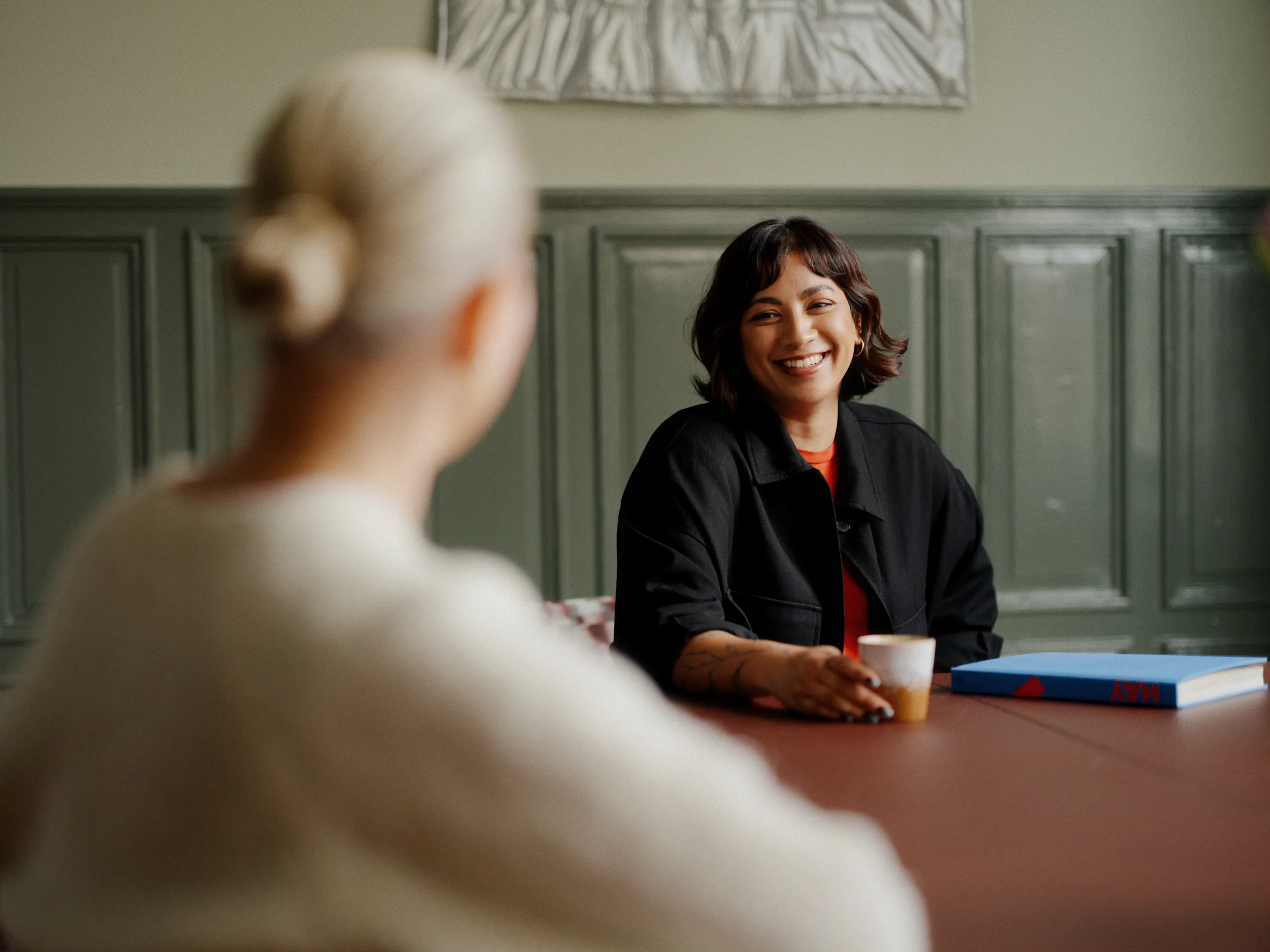 Smiling woman holding a coffee cup during a creative consultation.