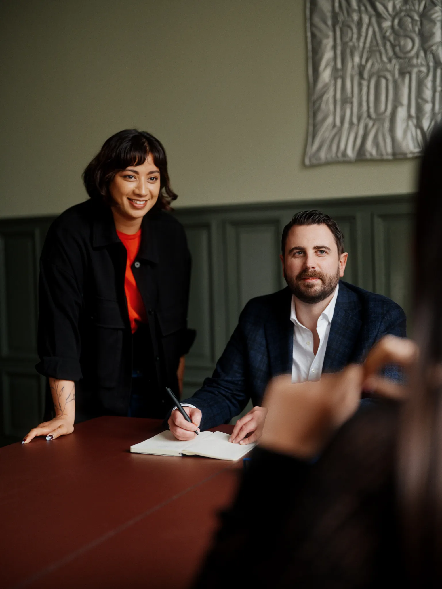Two consultants collaborating and taking notes at a conference table.