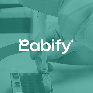 Gloved hand using a pipette to transfer liquid into a small vial in a laboratory setting with test tubes nearby, overlaid with the Labify logo.