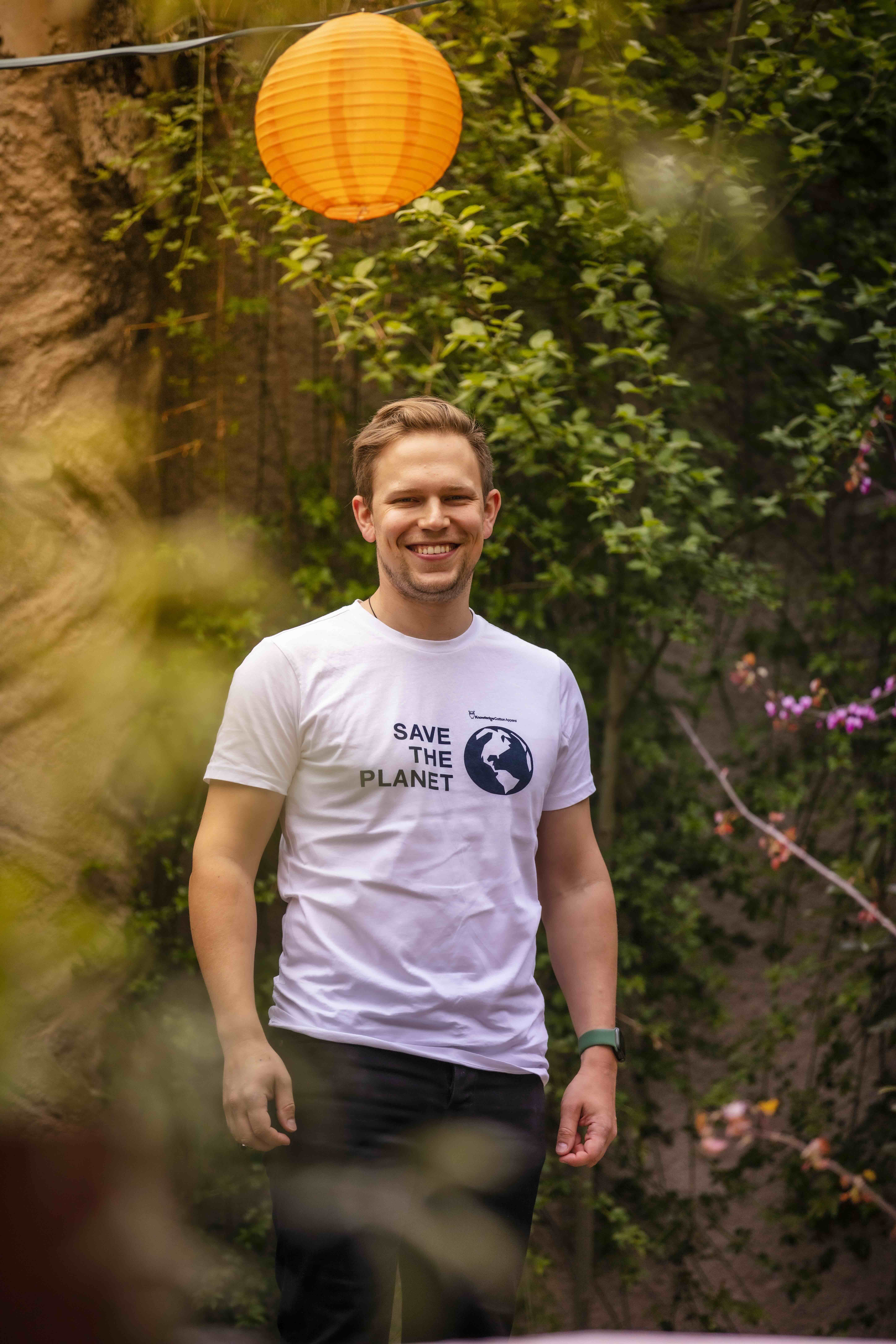Hoteldirektor Ben Förtsch vom Hotel Luise lächelt in die Kamera und trägt ein T-Shirt mit dem Schriftzug "Save the Planet"