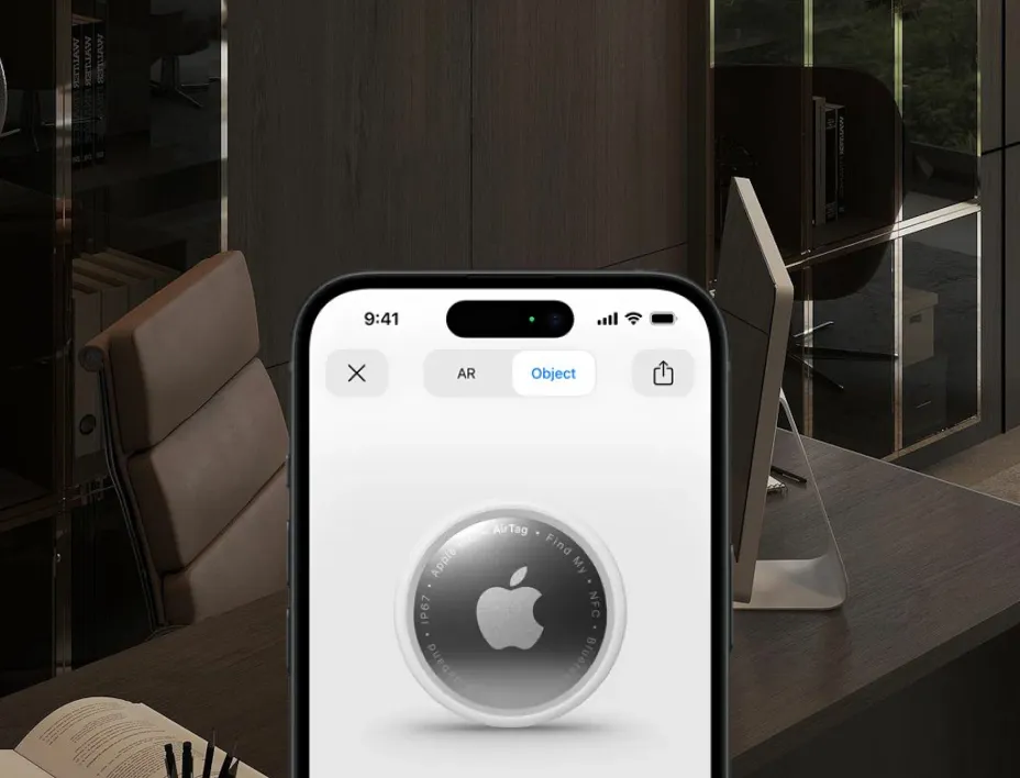 Smartphone screen showing an Apple AirTag in an app interface with office background.