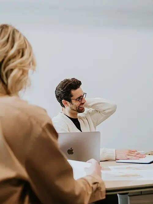 Two people sitting at a table with a laptop.
