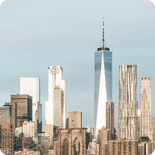 Skyline of Lower Manhattan featuring the One World Trade Center and Brooklyn Bridge on a clear day.