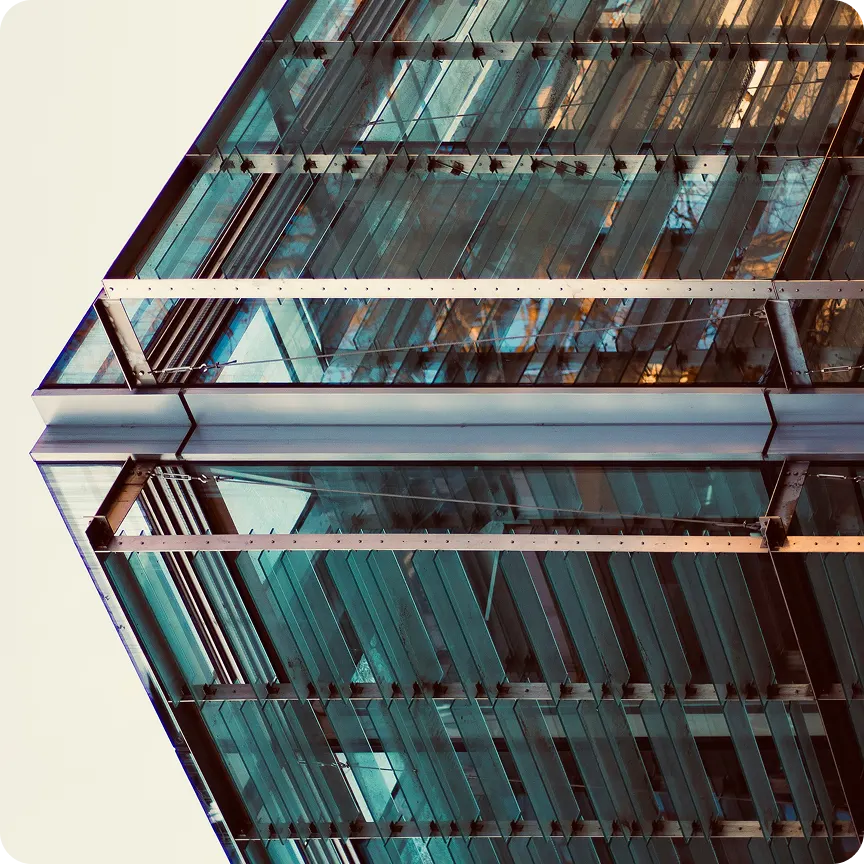 Bottom-up view of a modern glass building facade with metal supports and reflections.