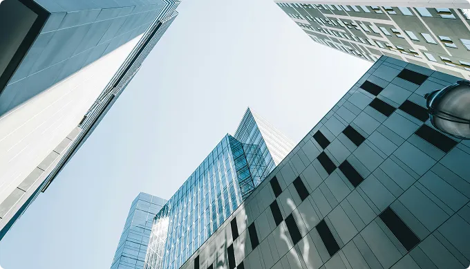Upward view of modern glass and concrete skyscrapers under clear sky.
