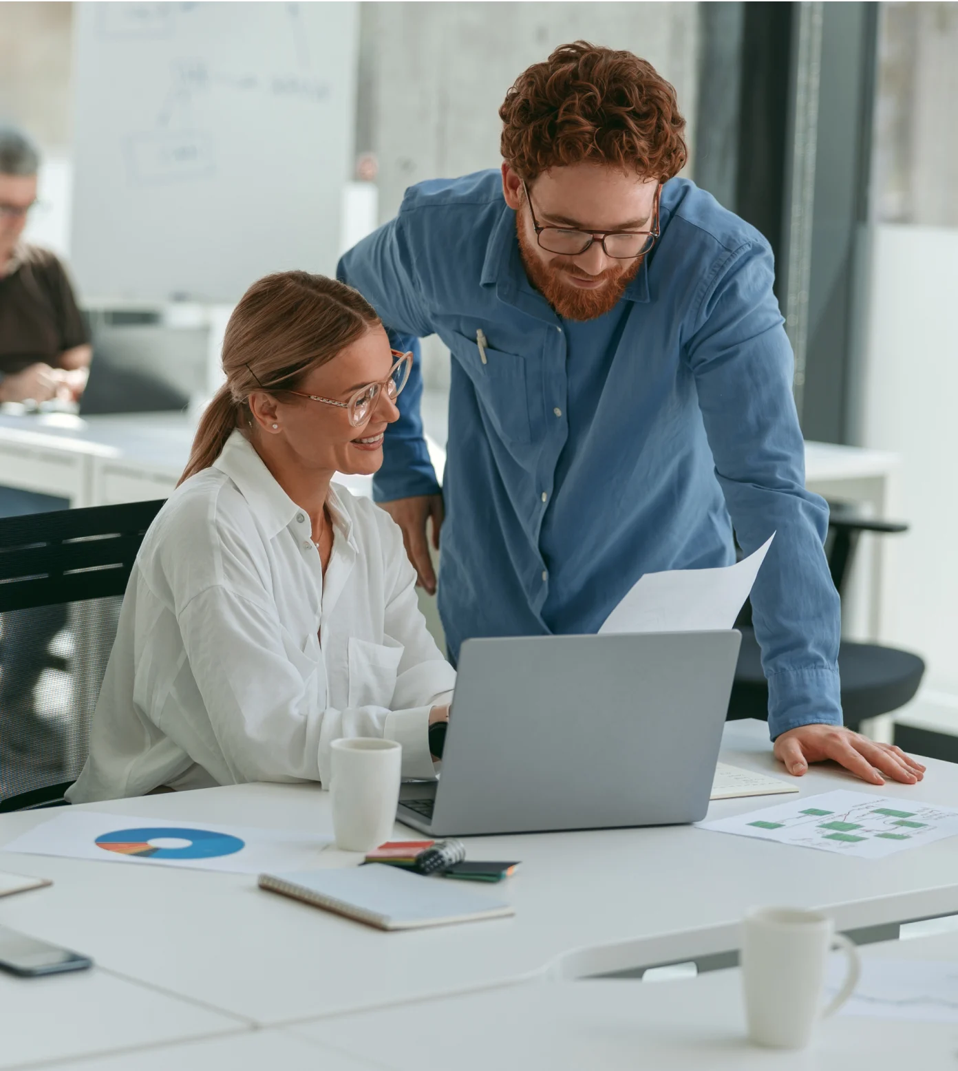 Two people sitting at a table with a laptop.
