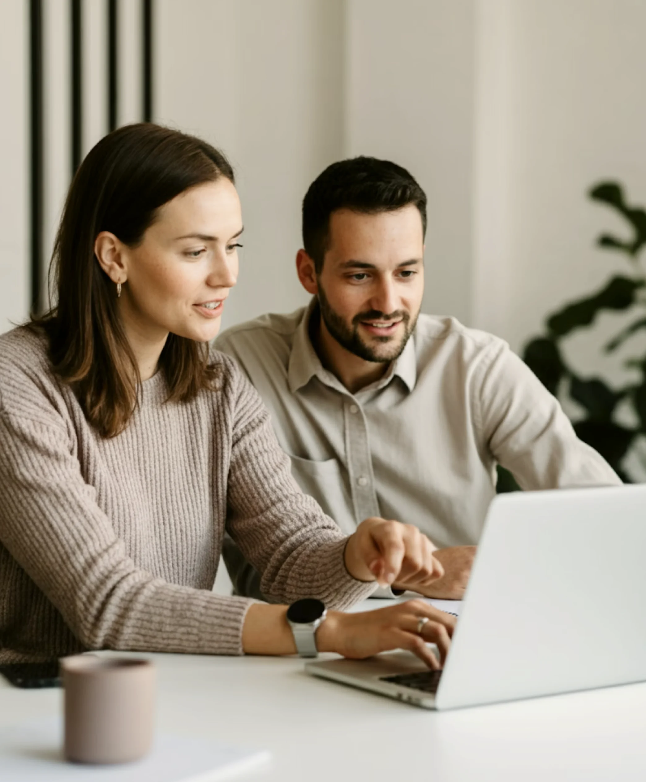 Two people sitting at a table with a laptop.