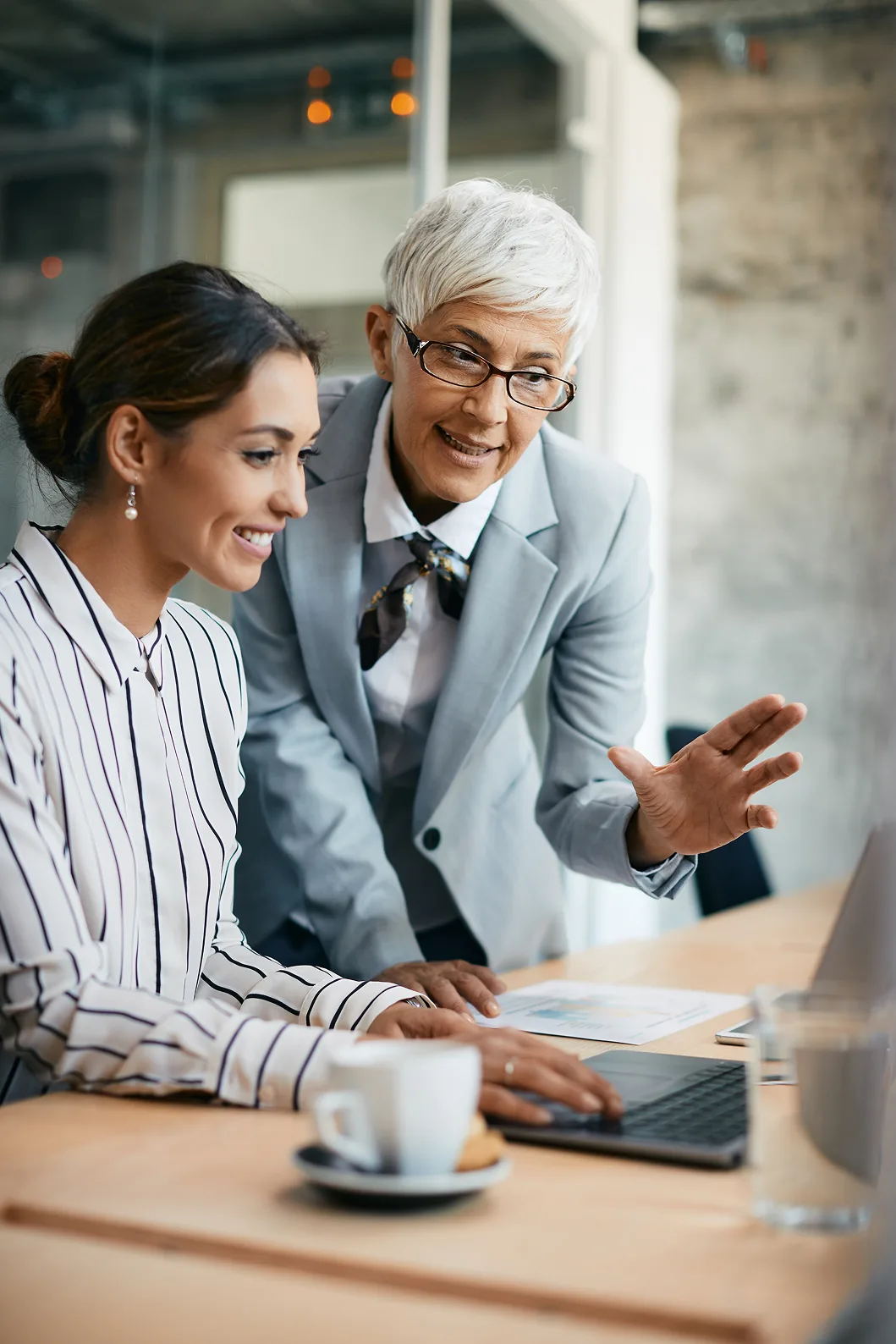 Two people sitting at a table with a laptop.