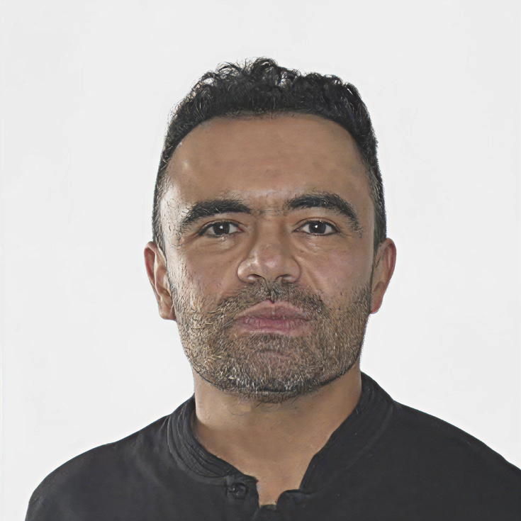 Man with short curly hair, full beard, and black shirt looking straight at the camera.