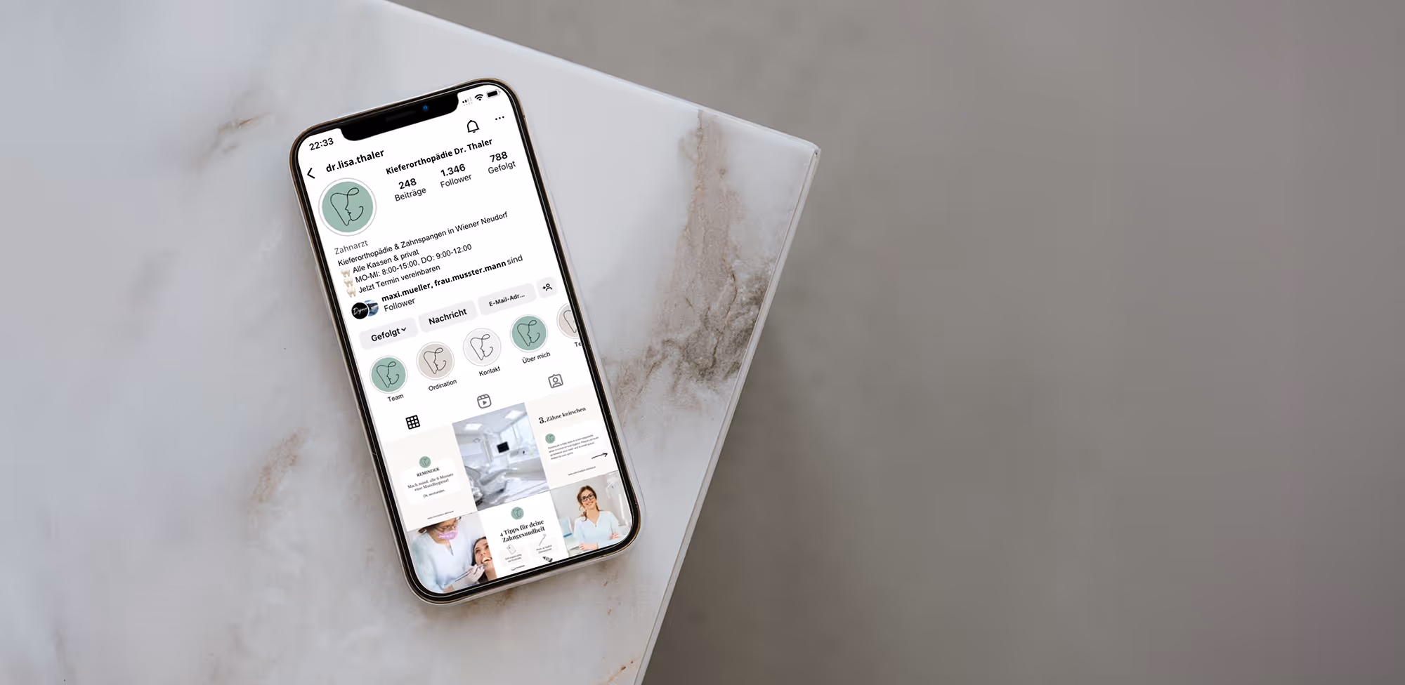 Smartphone auf Marmortisch, auf dem das Instagram-Profil des Kieferorthopäden Dr. Thaler mit Beiträgen und Symbolen angezeigt wird.