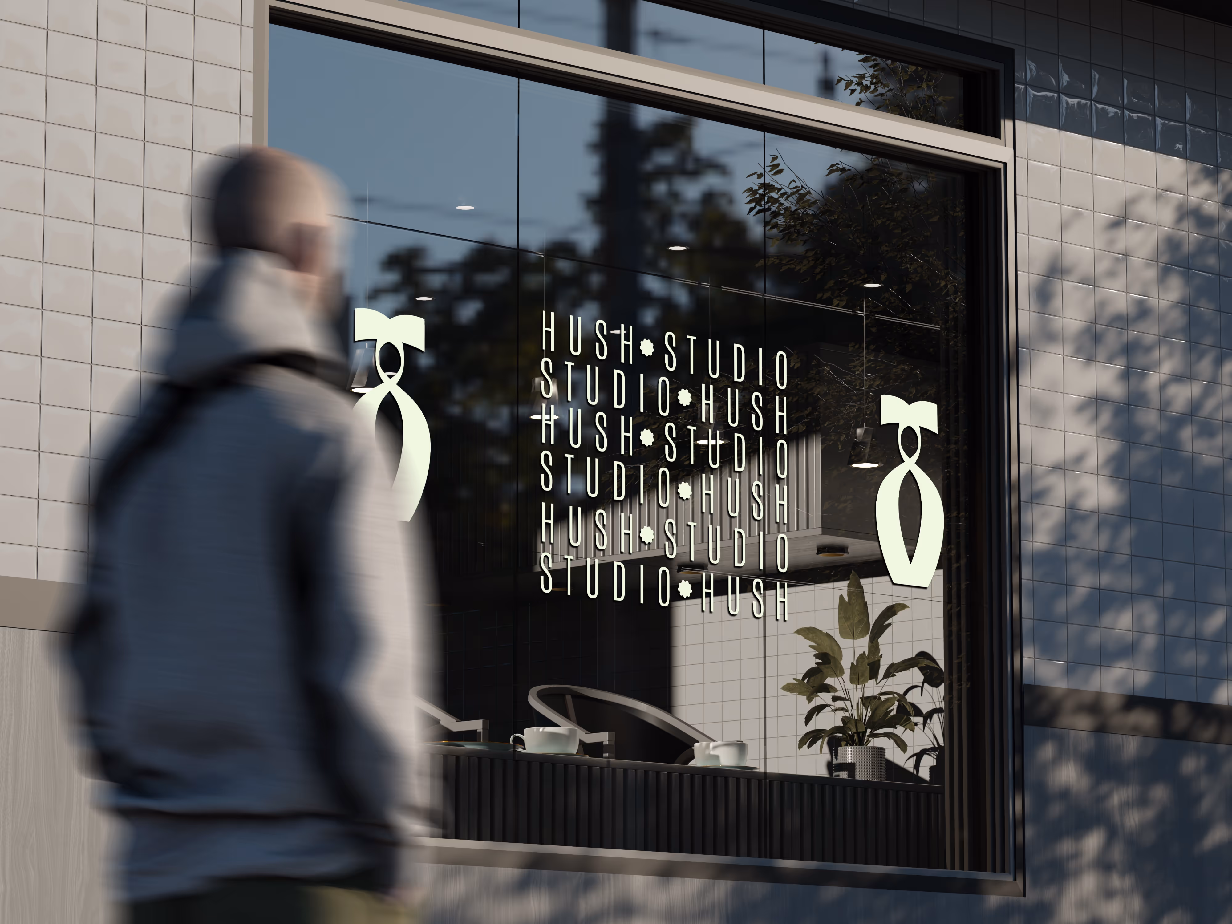 Blurred person walking past a modern storefront window with the text 'HUSH STUDIO' repeated and stylized abstract logos displayed.