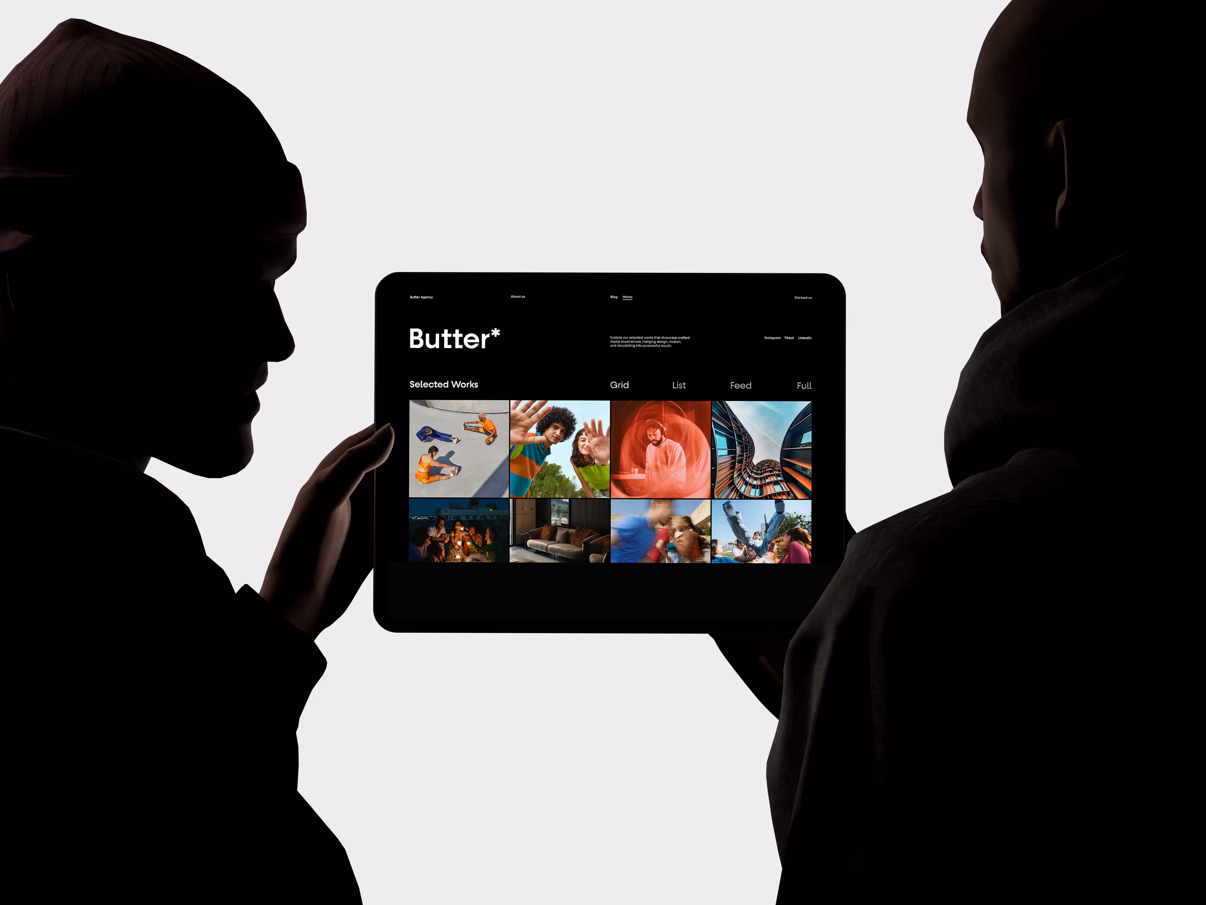 Silhouetted profiles of two people holding a tablet displaying the website for Butter with a grid of colorful images.