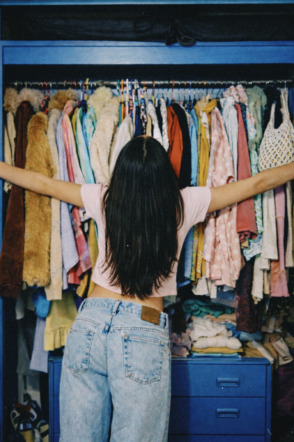 Persona de espaldas eligiendo ropa en un armario lleno de prendas