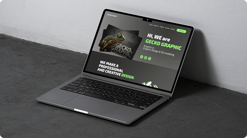 Open laptop on dark floor showing a website homepage with green and white text and a gecko image.