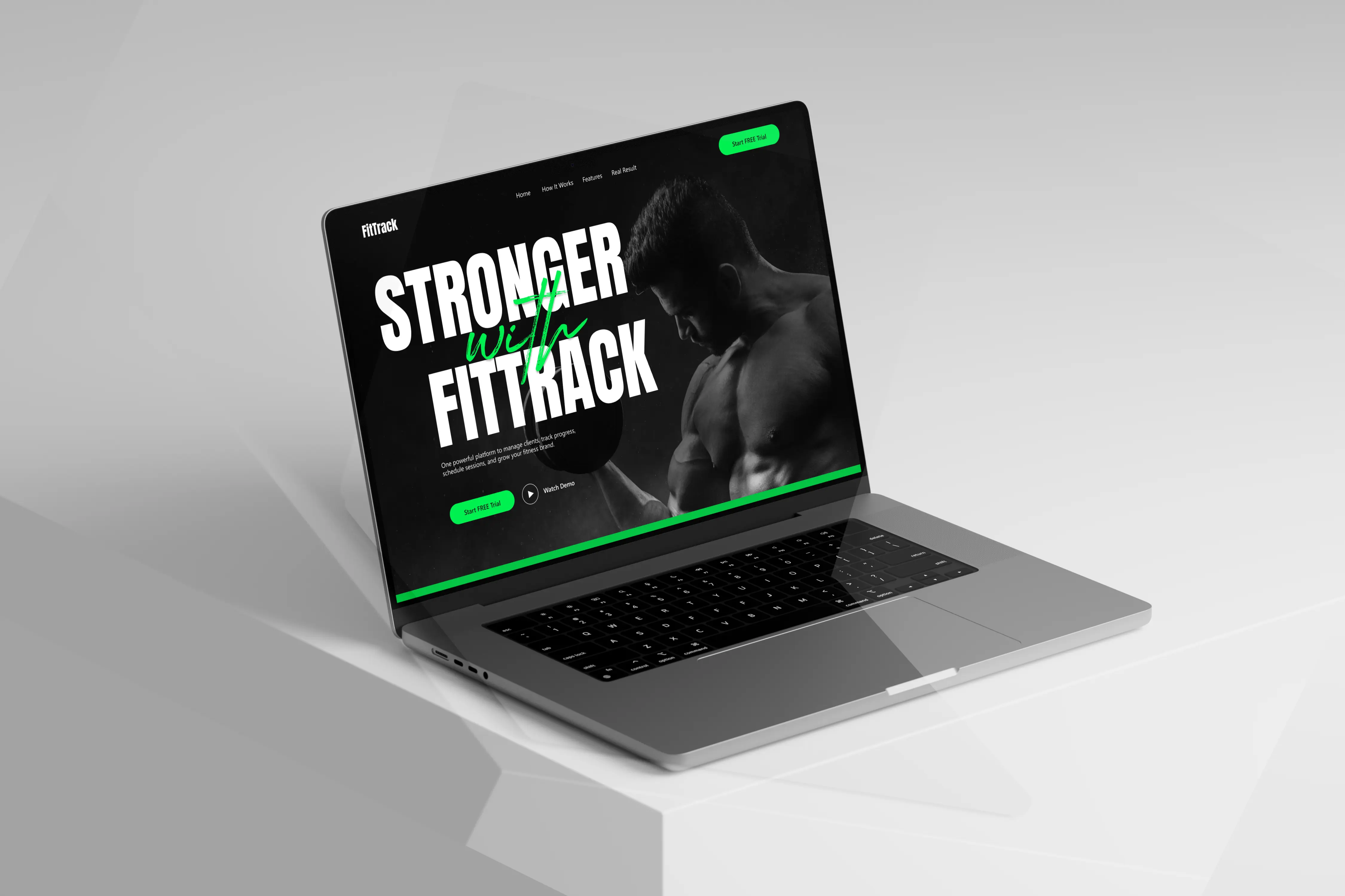 Open laptop displaying a fitness website homepage with a muscular man lifting weights and text 'Stronger with Fittrack'.