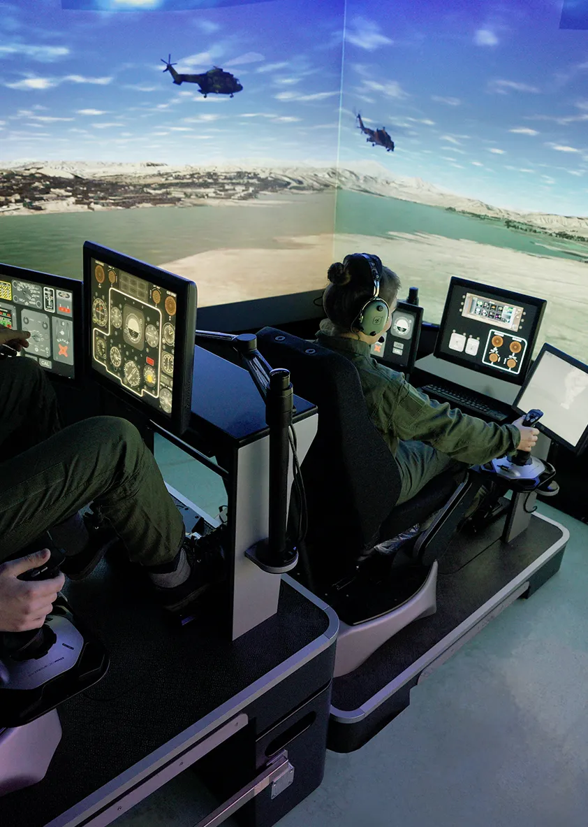Two people using a high-tech helicopter simulation device. 