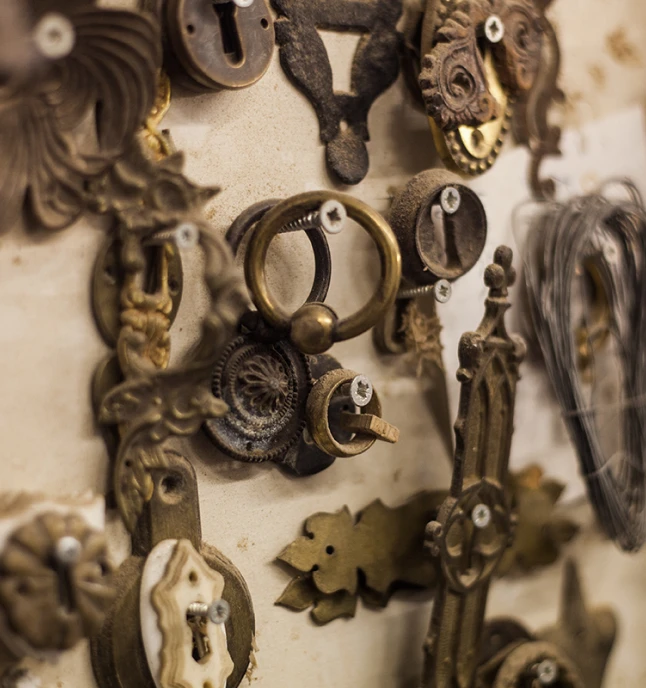 Verschiedene antike Messing- und Metallbeschläge und Schlüssellöcher an einer Wand montiert.