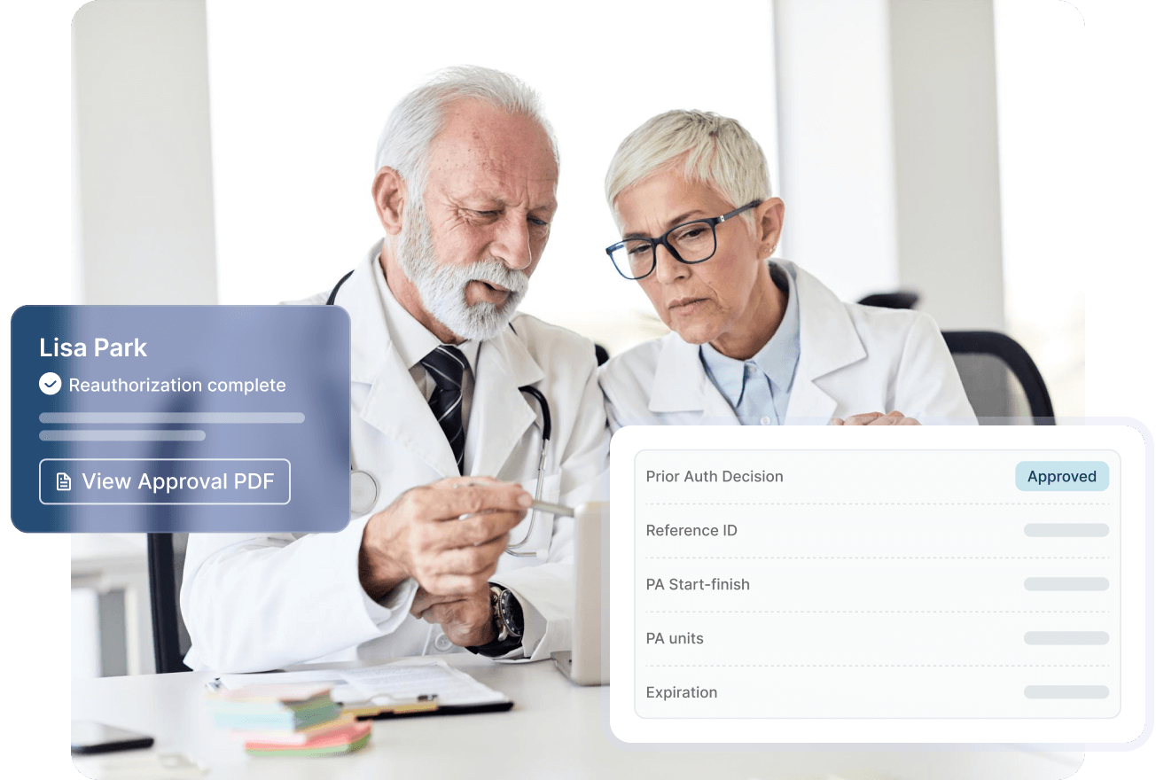 Smiling male doctor in blue scrubs with a stethoscope working on a laptop at a desk.
