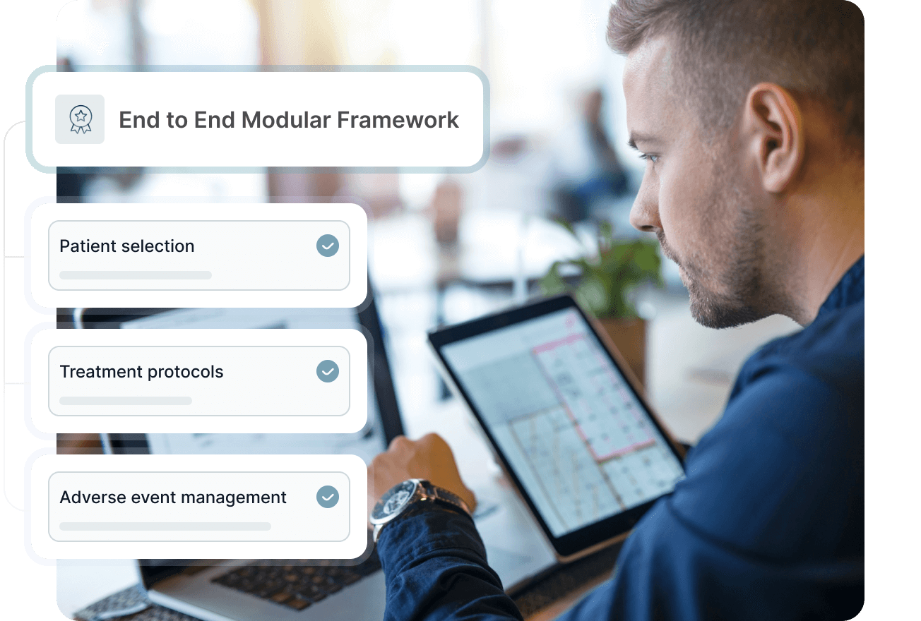 Smiling male healthcare professional in blue scrubs with stethoscope working on a laptop in an office.