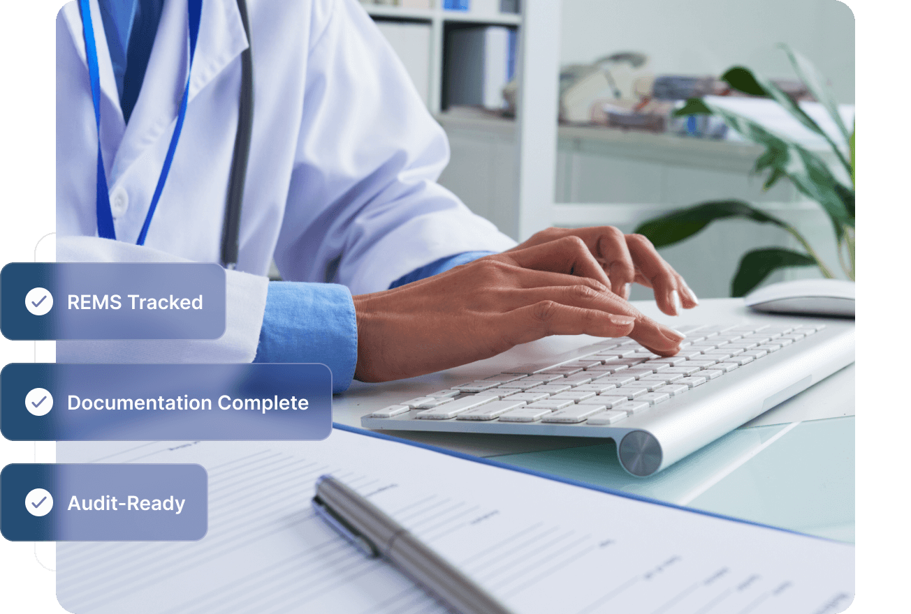 Smiling male healthcare professional in blue scrubs with stethoscope working on a laptop in an office.