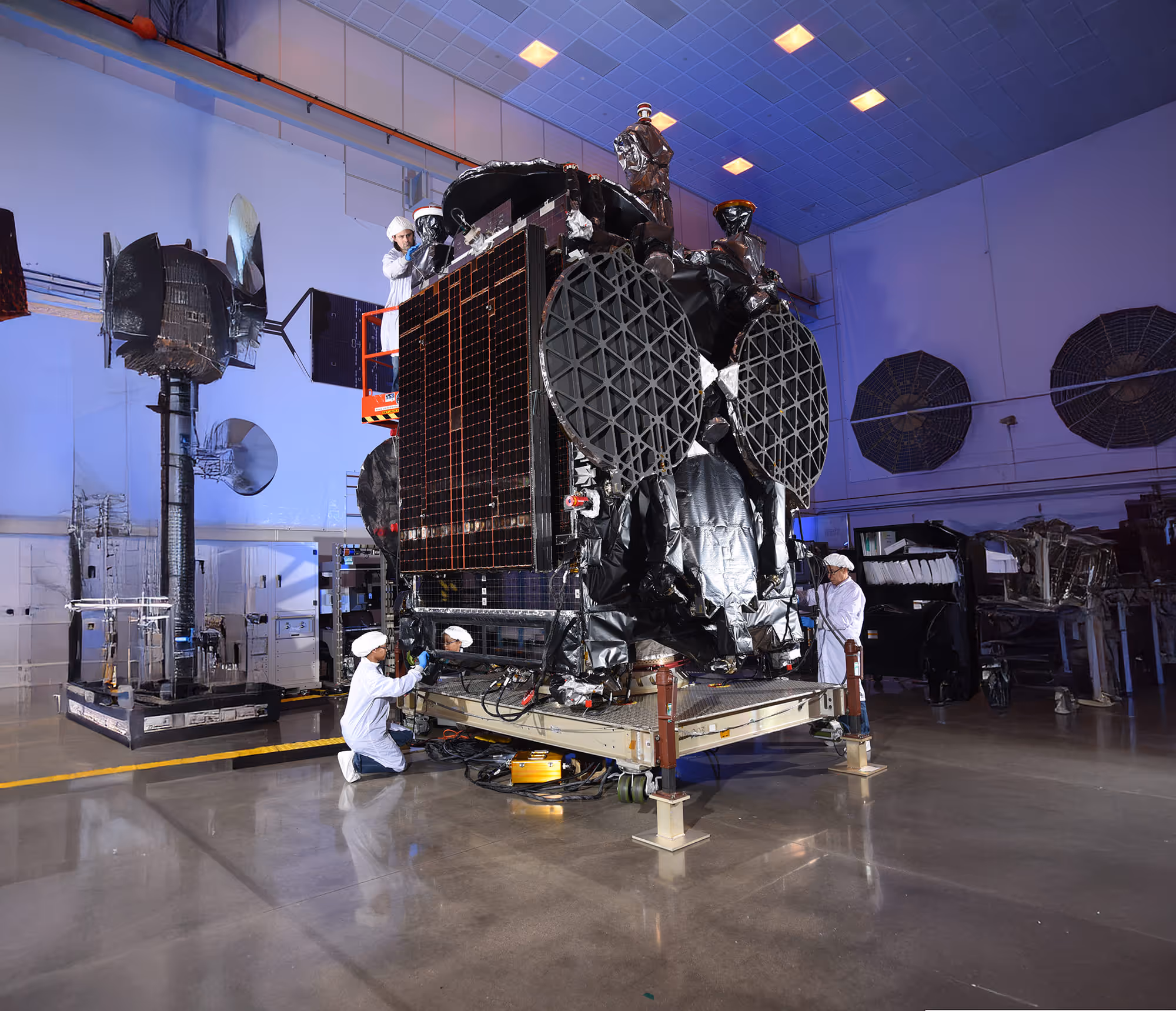 Technicians in white cleanroom suits working on the GovSat-2 satellite.