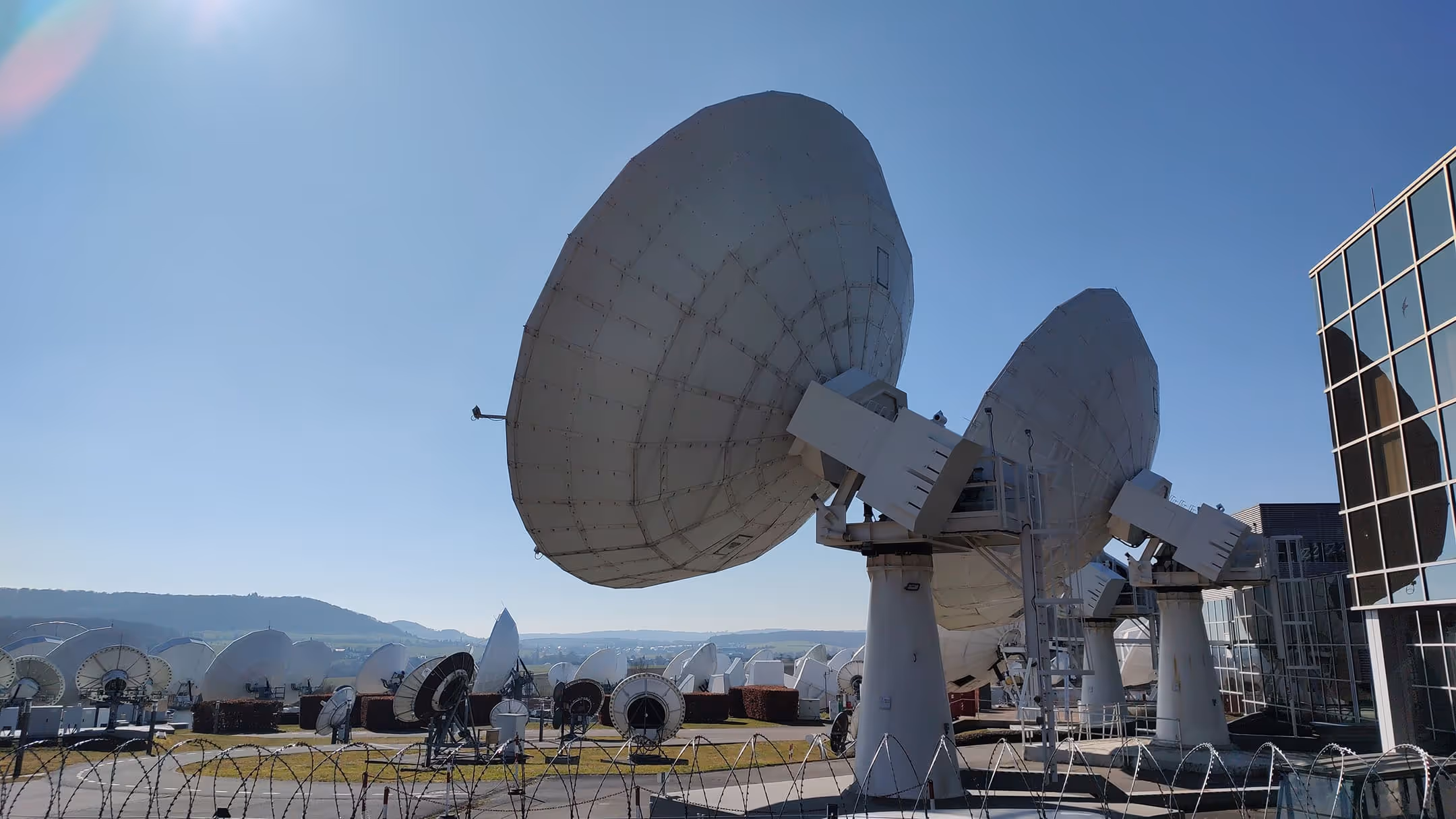 Large satellite dishes arranged outdoors under a clear blue sky next to the GovSat building.