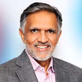 Smiling middle-aged man with gray hair and beard, wearing a gray blazer and light pink shirt.