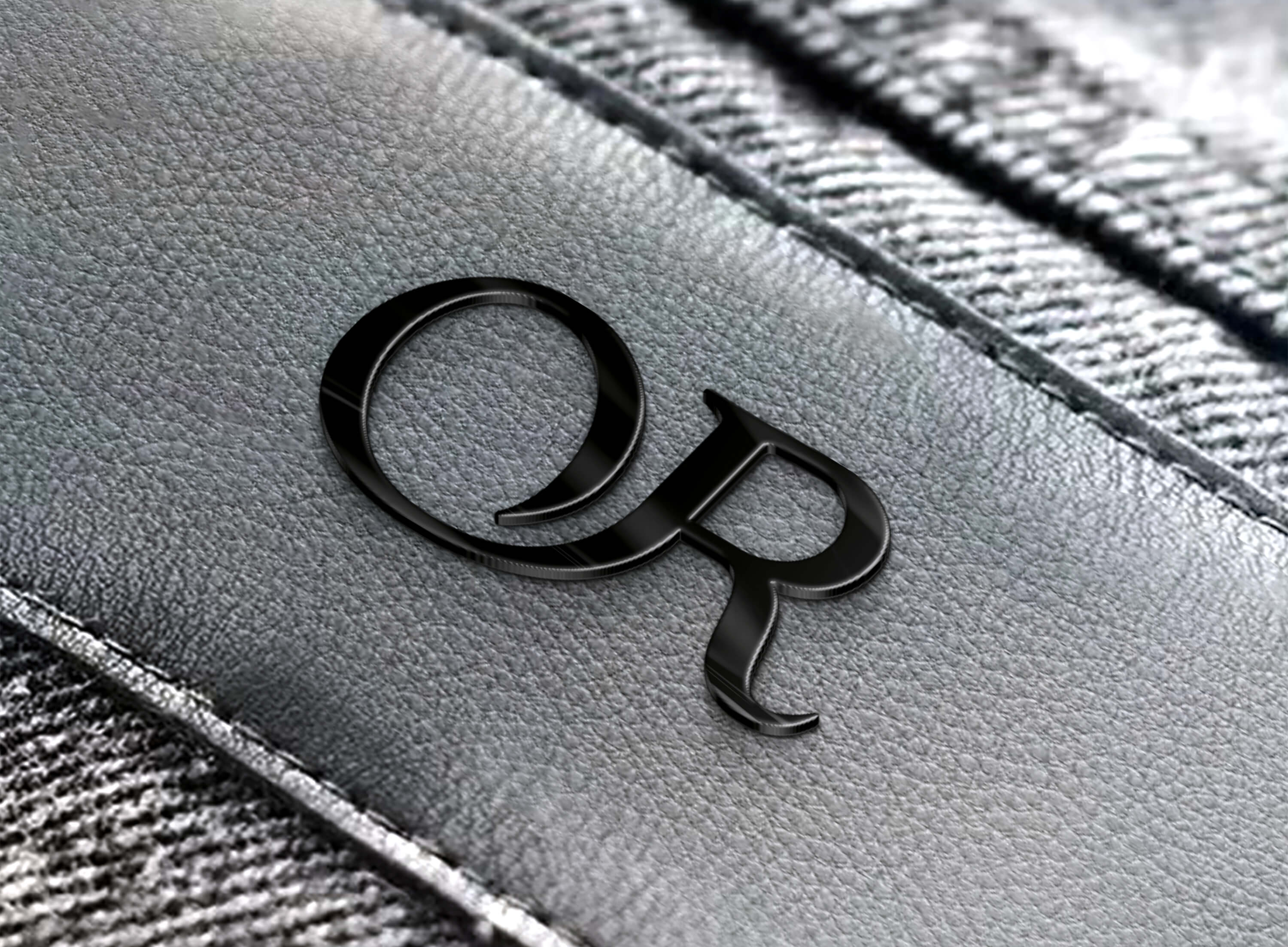 Schwarzes Logo mit den Buchstaben O und R auf grauem Lederetikett, angenäht an graue Jeans.