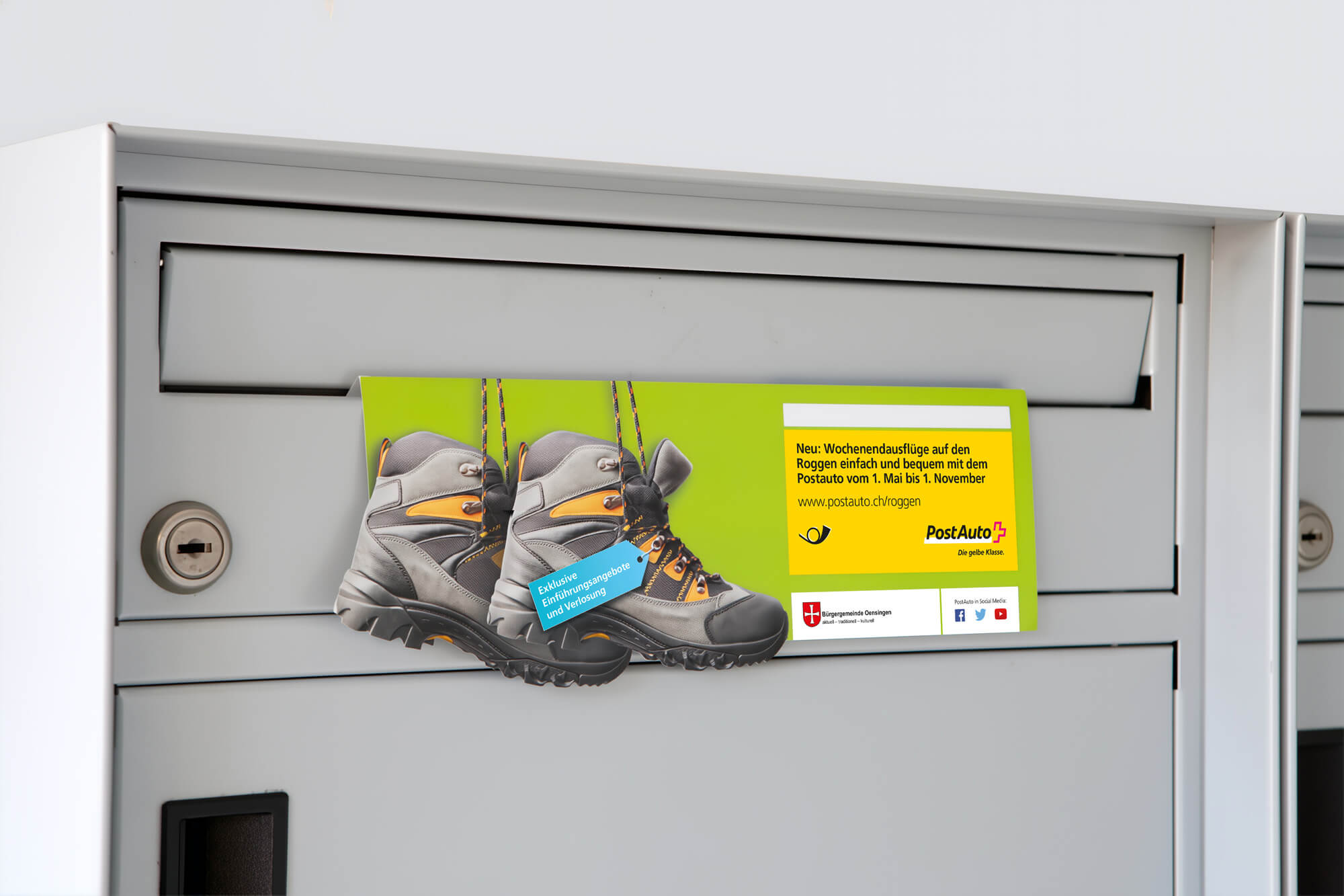 Flyer mit Wanderstiefeln neben Text zu Wochenendausflügen mit Postauto von Mai bis November in einem Briefkasten.