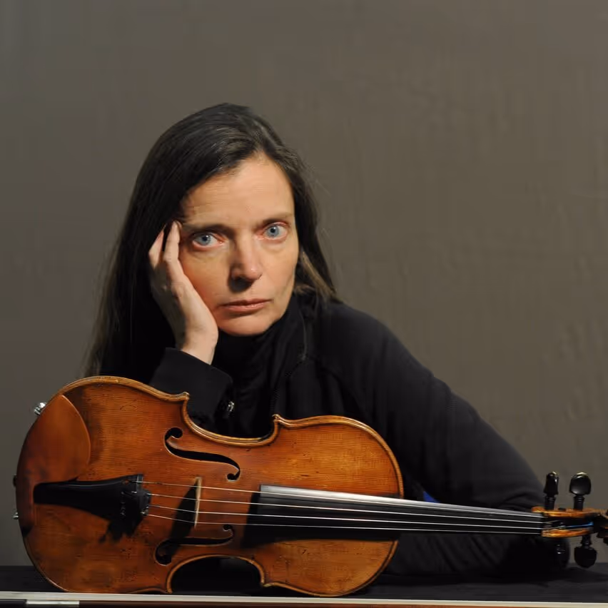 Man intensely playing a marimba with four mallets in an ornate room with decorative wallpaper and architectural details.