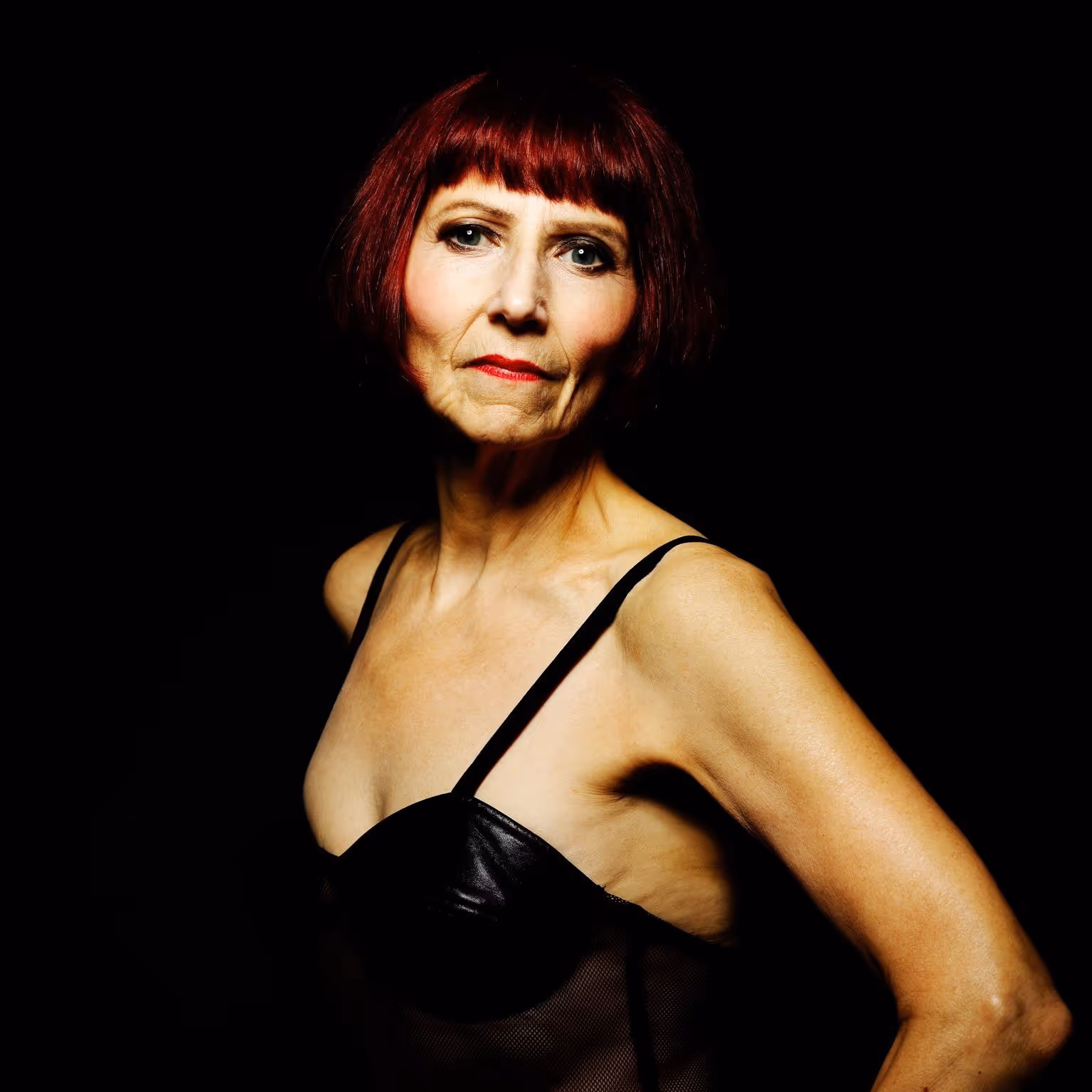 Four men in black suits standing outdoors holding string instruments, including violins and a cello, against a cloudy sky.