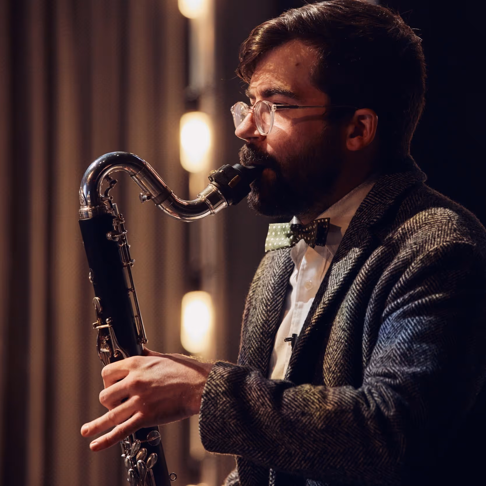 Woman playing a violin, wearing a black lace dress against a dark background.