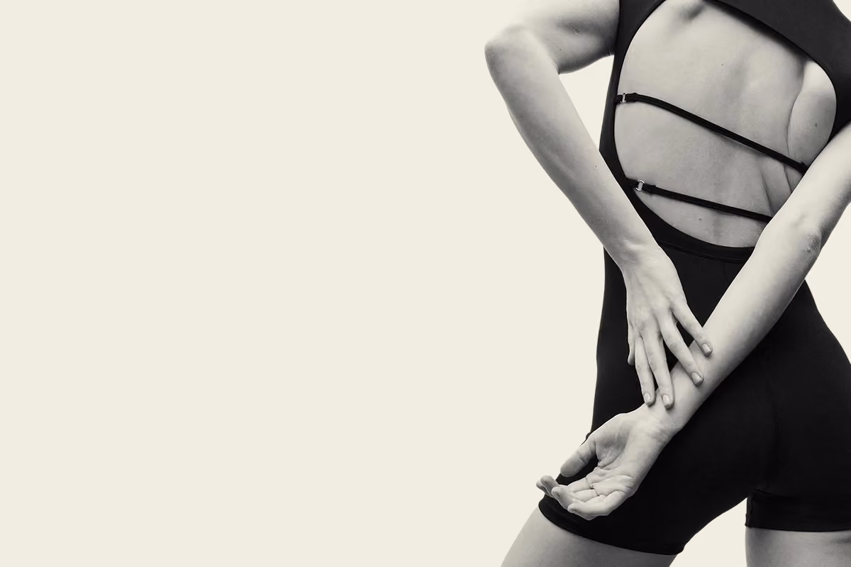 Woman in a Pilates pose against a warm neutral background