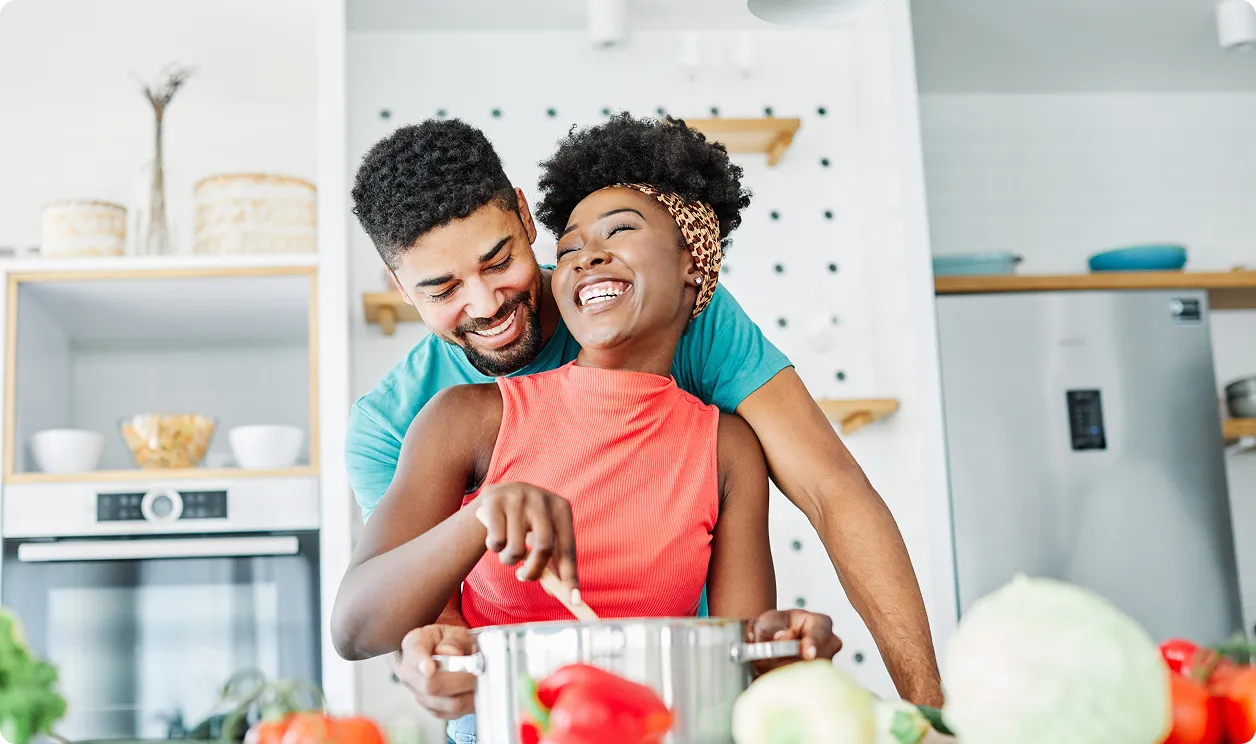 Un couple heureux cuisine ensemble dans une cuisine moderne avec des légumes frais sur le comptoir.
