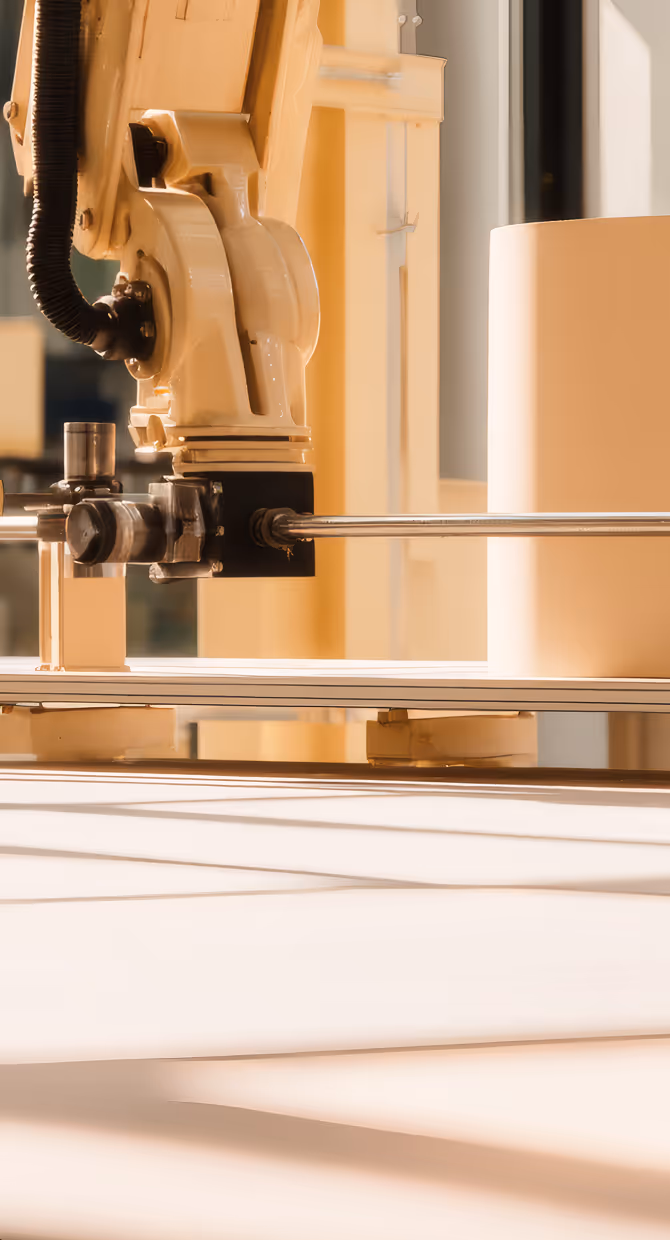 Close-up of an industrial robotic arm with metal components in a bright workspace.