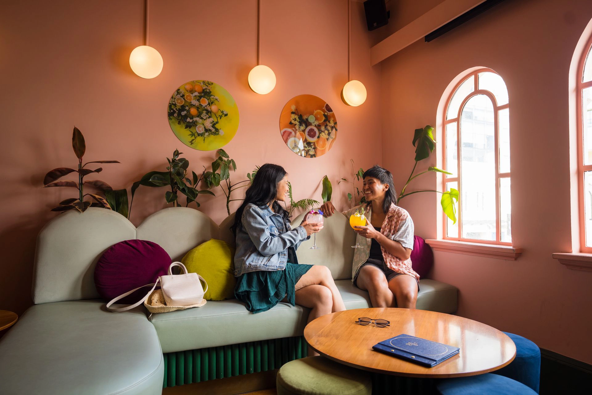 Interior of a wooden sauna room with tiered benches and a large window overlooking a beach and ocean view with a pier.