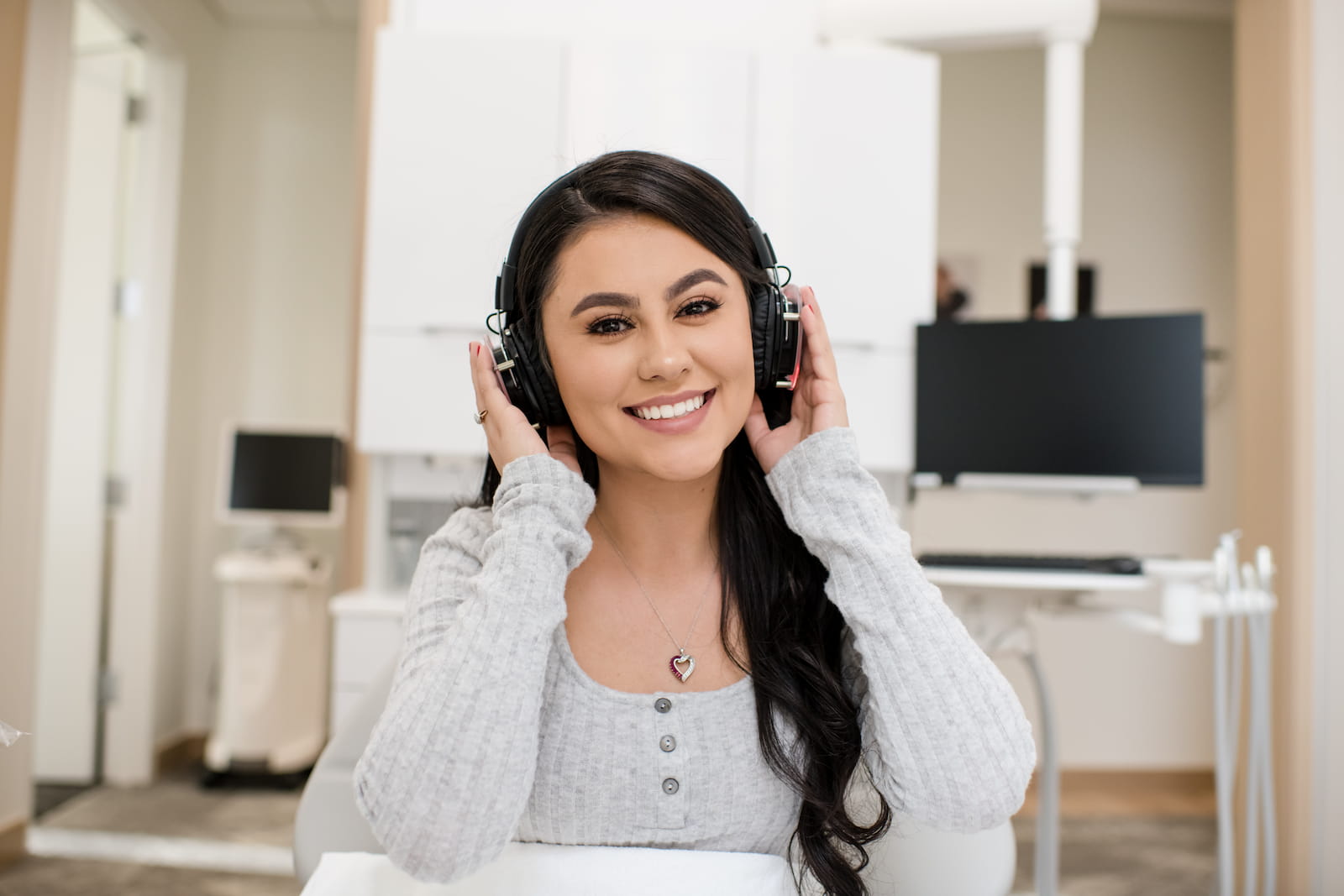 A smiling patient at Tranquility Dental Wellness wears headphones and relaxes in the treatment chair.