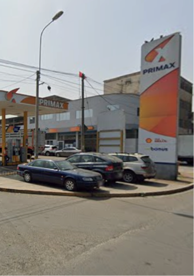 Estación de servicio Primax con varios autos estacionados frente a los surtidores bajo un cielo despejado.