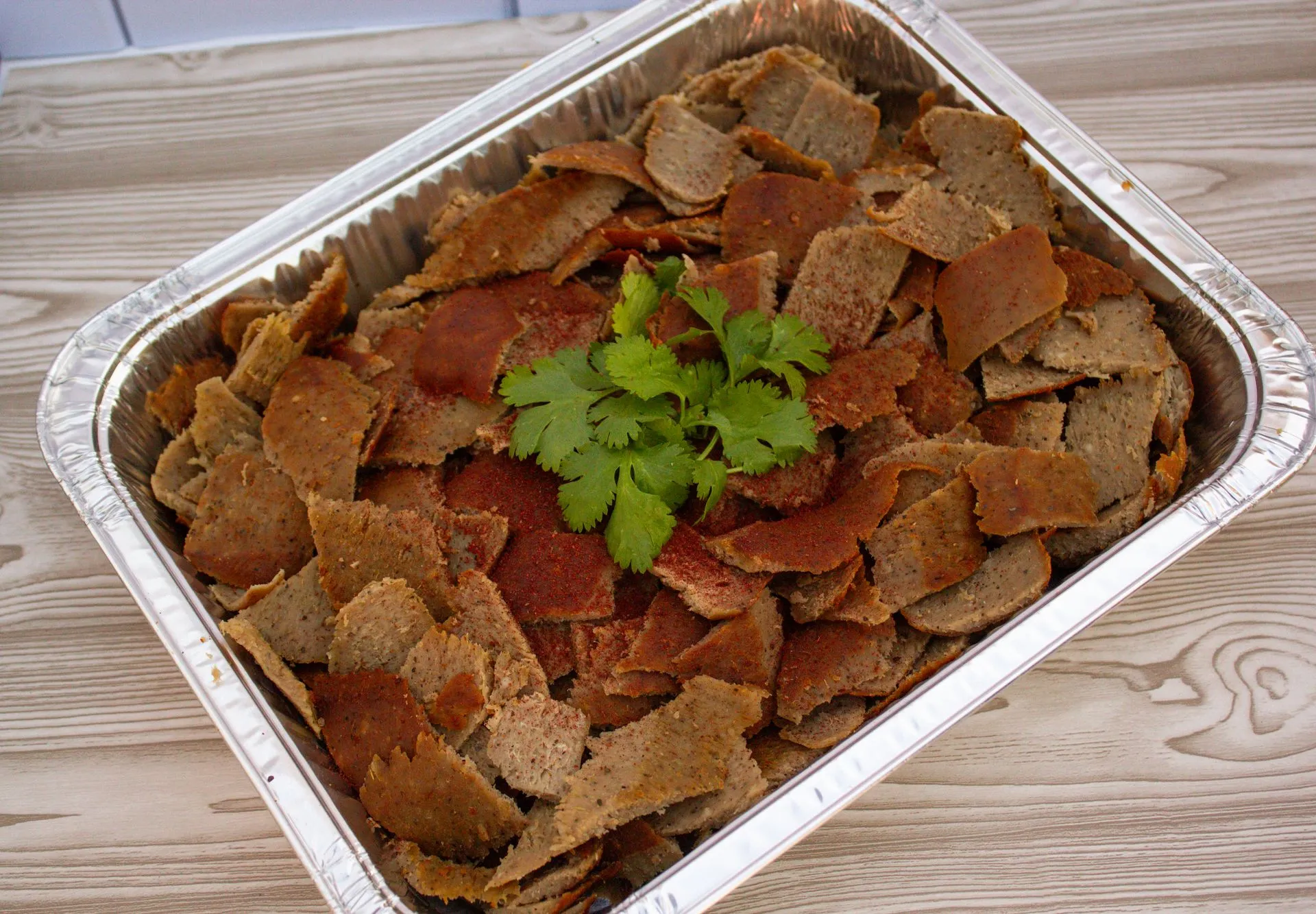 A tray of meat and a green herb.