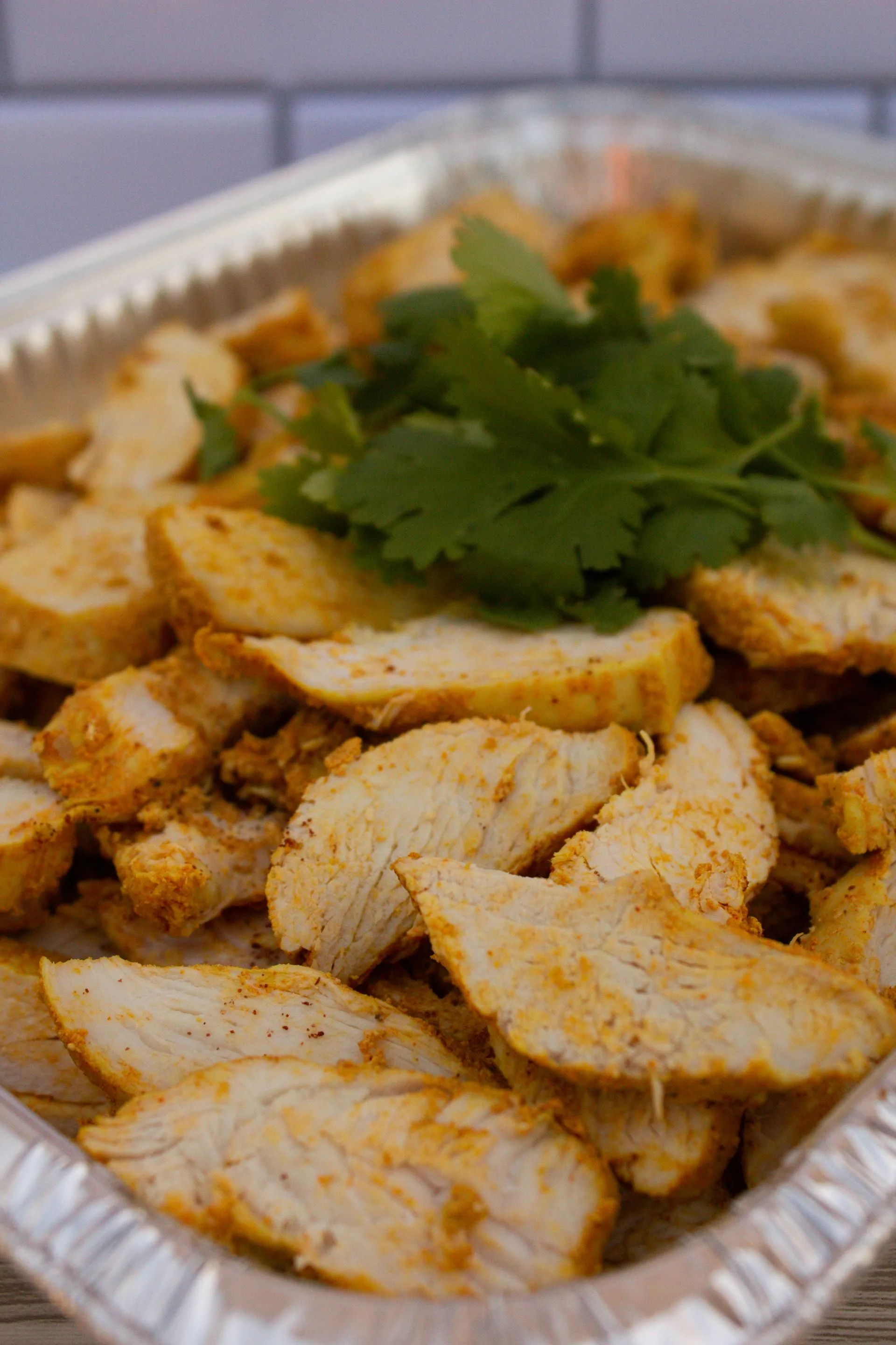 A close up of a piece of chicken with a green herb on top.