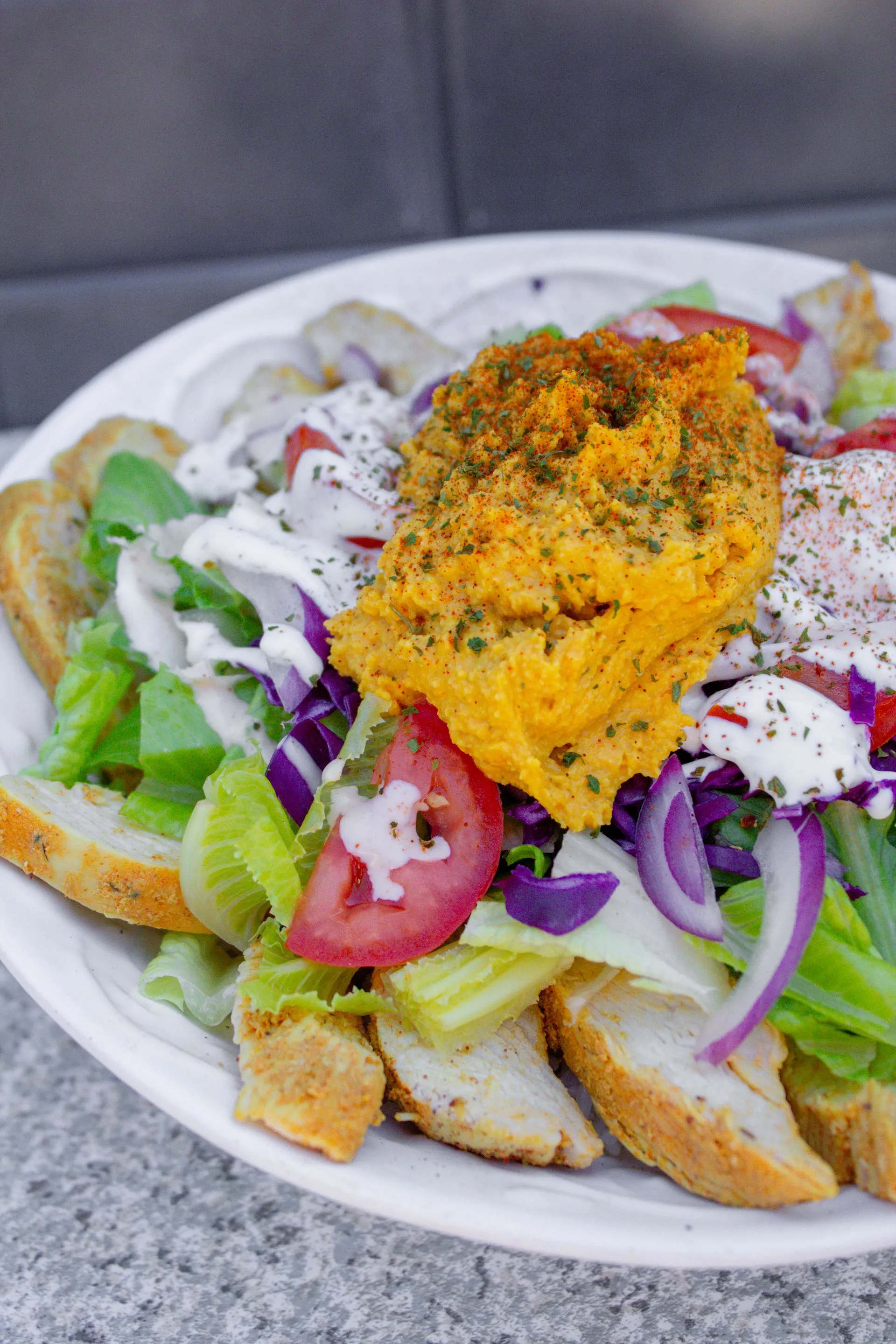 A white plate with a salad and a piece of bread.