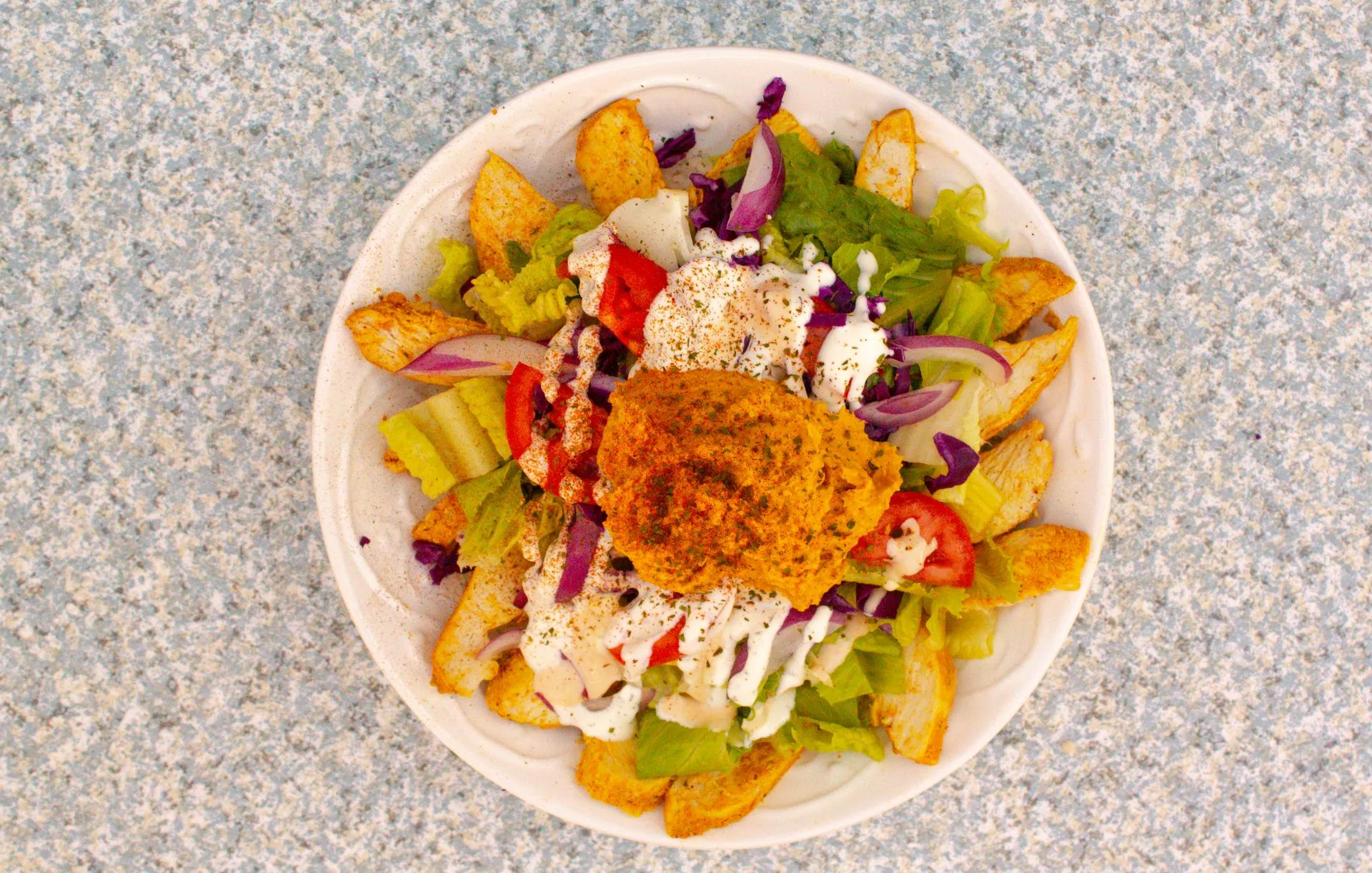 A white plate with a salad and fries on it.
