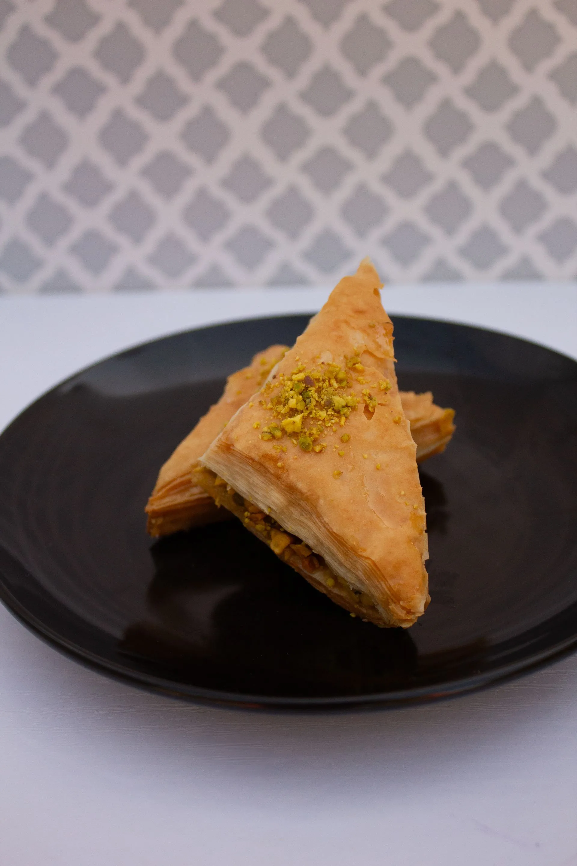 A black plate with a triangle shaped pastry on it.