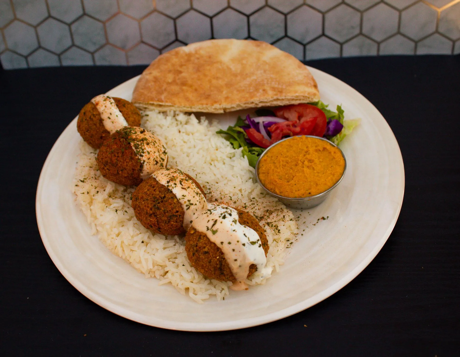 A plate of food with rice, meatballs, and sauce.