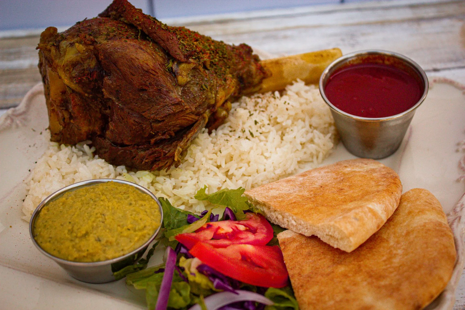 A plate of food with rice, tomatoes, lettuce, and a sauce.