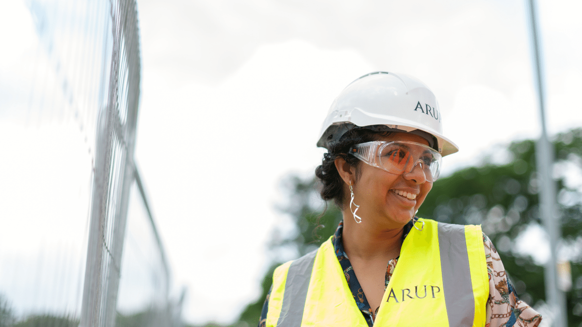 Smiling engineer in hard hat and safety vest at construction site