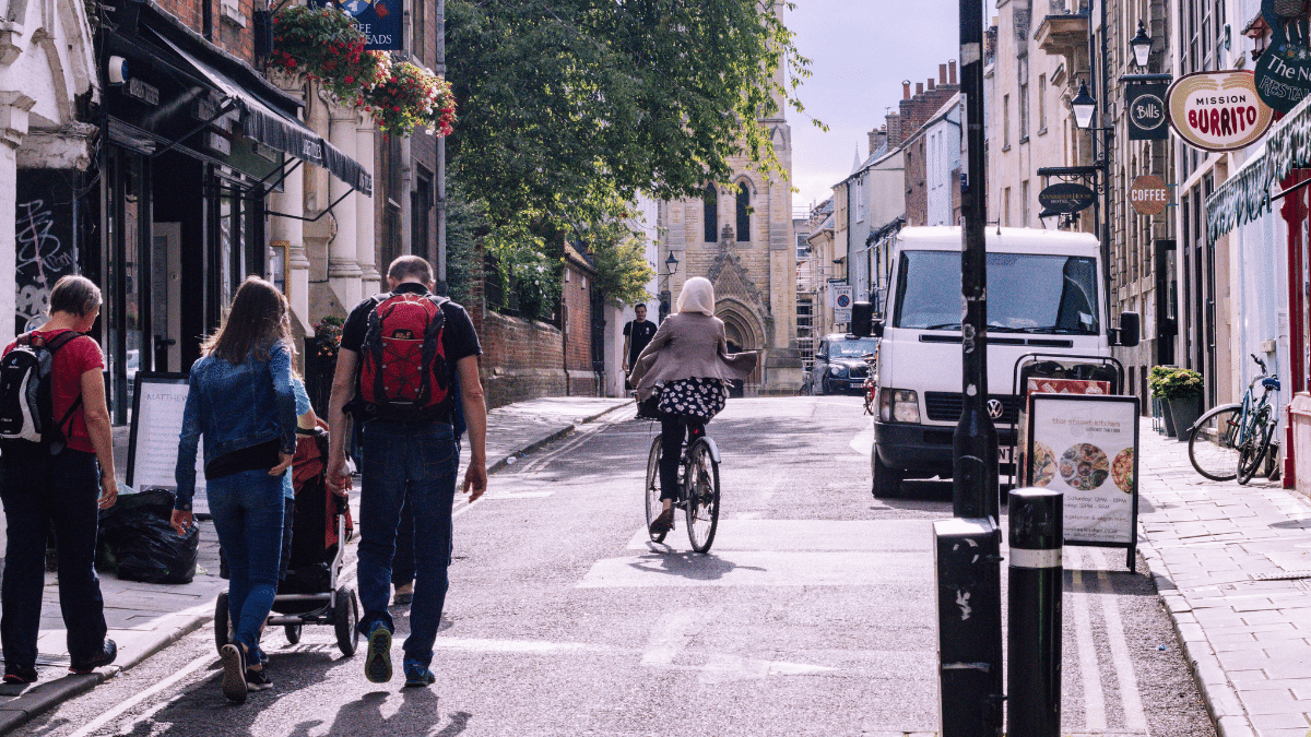 Busy street scene with pedestrians, cyclist, and historic buildings