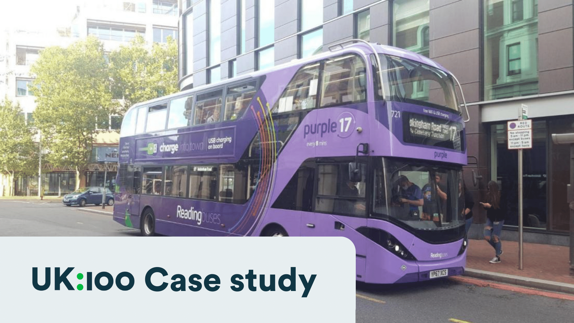 Purple double-decker bus with USB charging, parked at urban bus stop