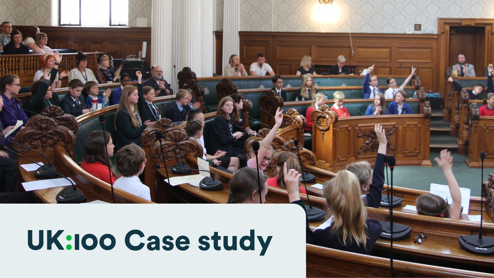 Students in formal attire participate in mock parliamentary debate with raised hands