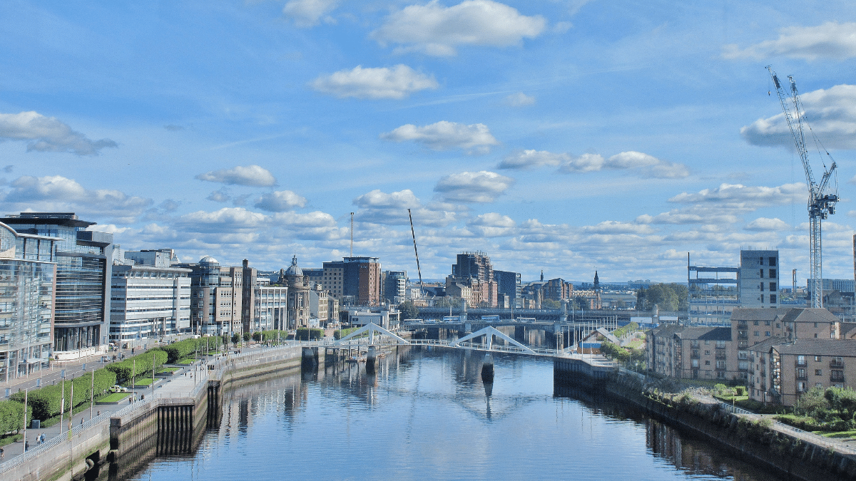 Glasgow cityscape with river, bridges, modern buildings, and fluffy clouds